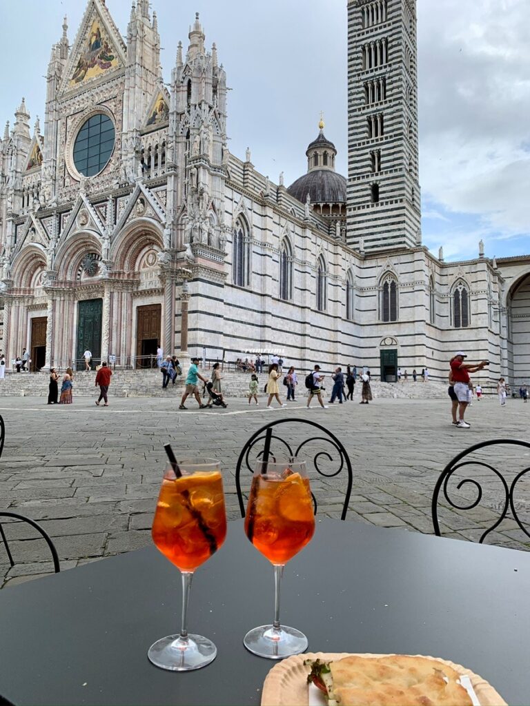Is Siena Italy Worth Visiting? A Realistic 2026 Day Trip Guide Relaxing at Piazza del Campo in Siena Italy with a drink