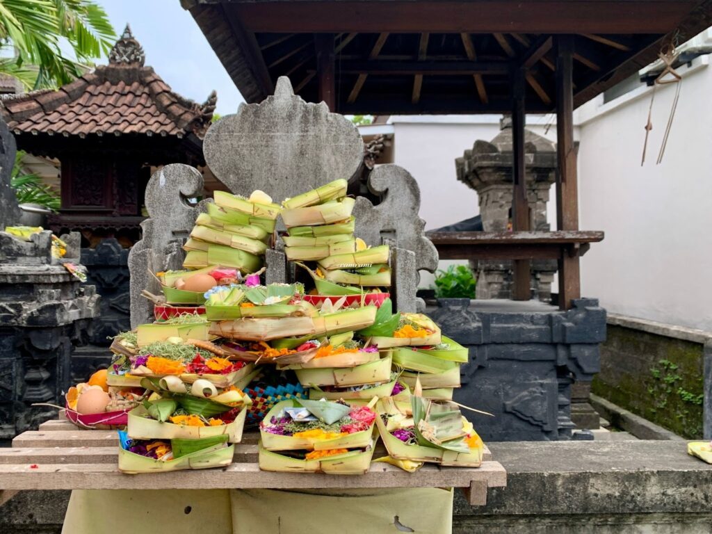 Multiple Canang Sari offerings stacked at a Balinese temple shrine